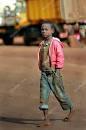 Dark skinned African boy walking barefoot in dirty jeans. 64689063
